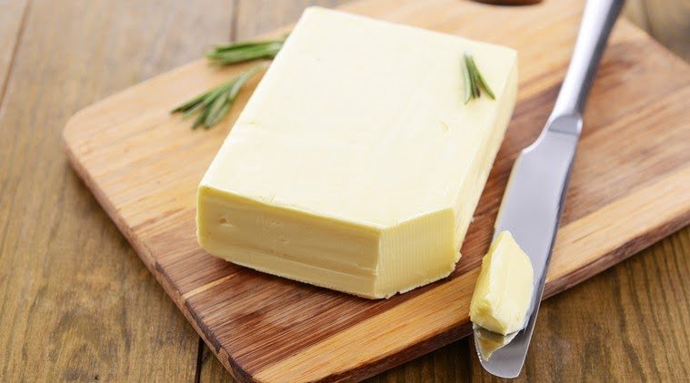 Tasty butter on wooden cutting board
