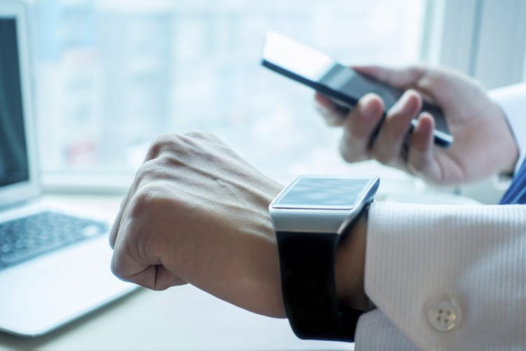 Businessman using his smartwatch and phone in office