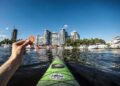 白天在城市建筑物附近的水面上举行绿色皮划艇的人