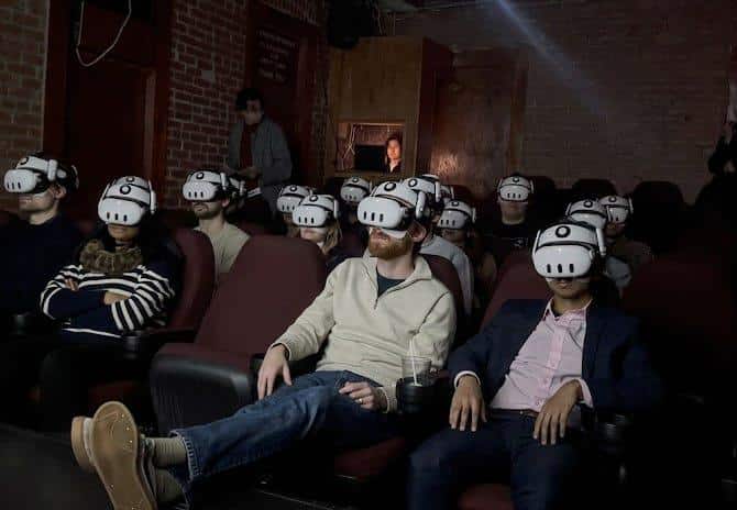 cinema VR spettatori con visori in sala oscura immersiva