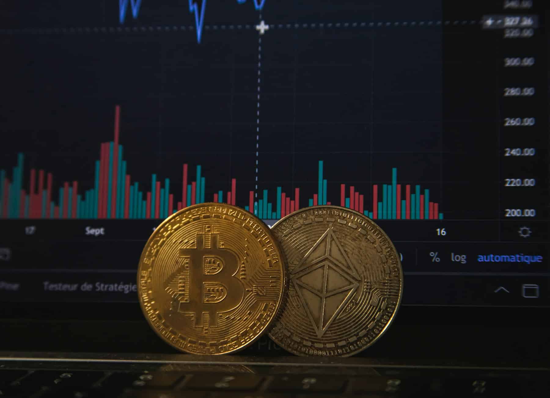 Monete di bitcoin ed ether davanti a un grafico di trading su un laptop. Binance