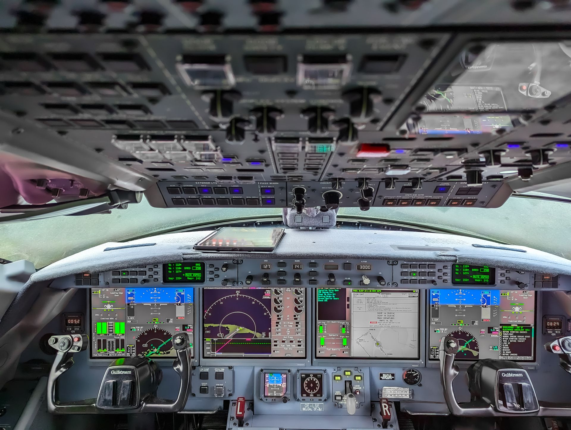 Cabina di pilotaggio di un jet con i display di navigazione e le due cloche davanti ai sedili. Contrails