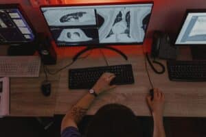 Una persona di spalle lavora al computer davanti a monitor con scansioni del torace. Perdita di competenze