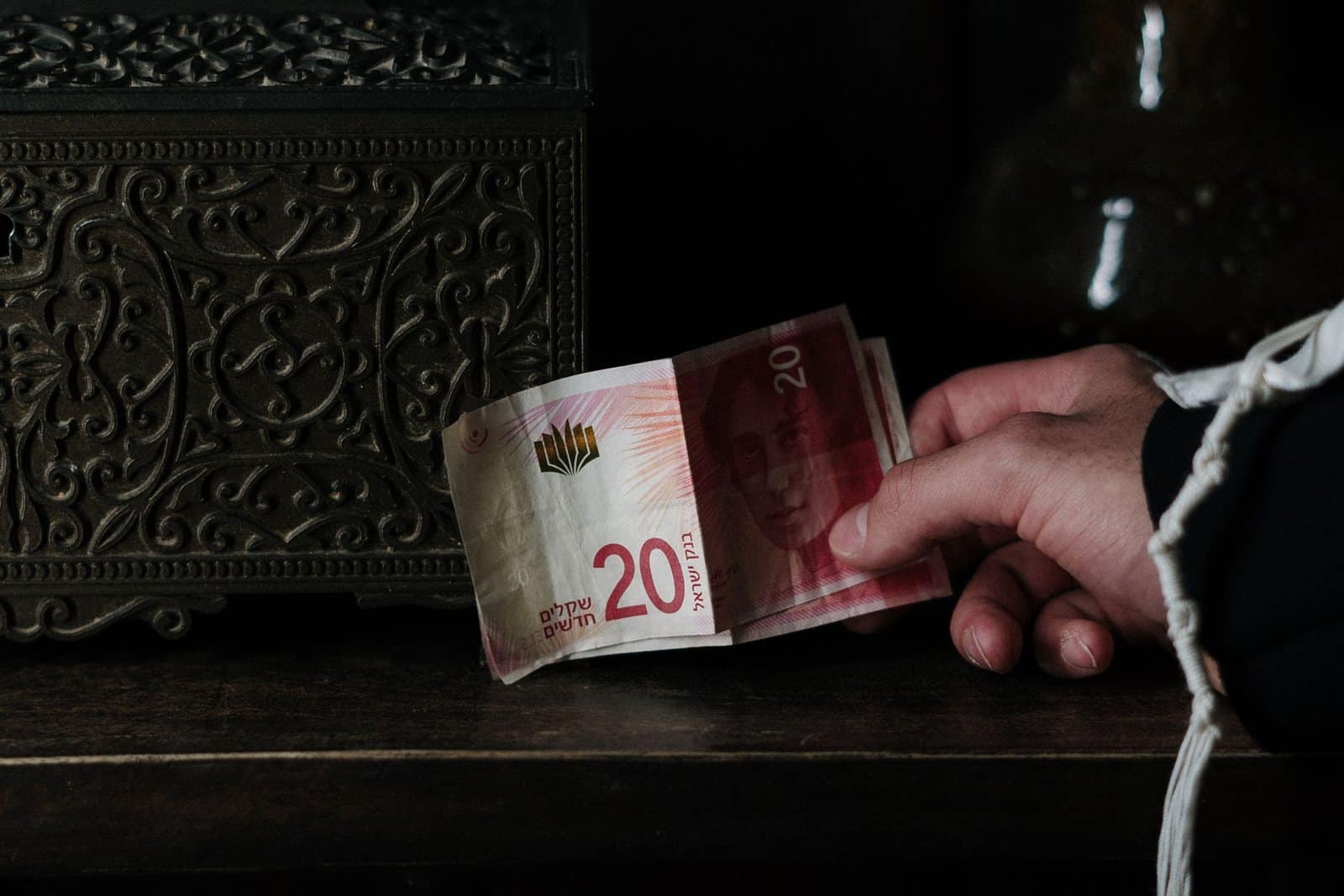 Economia israeliana: una mano tiene una banconota da 20 shekel