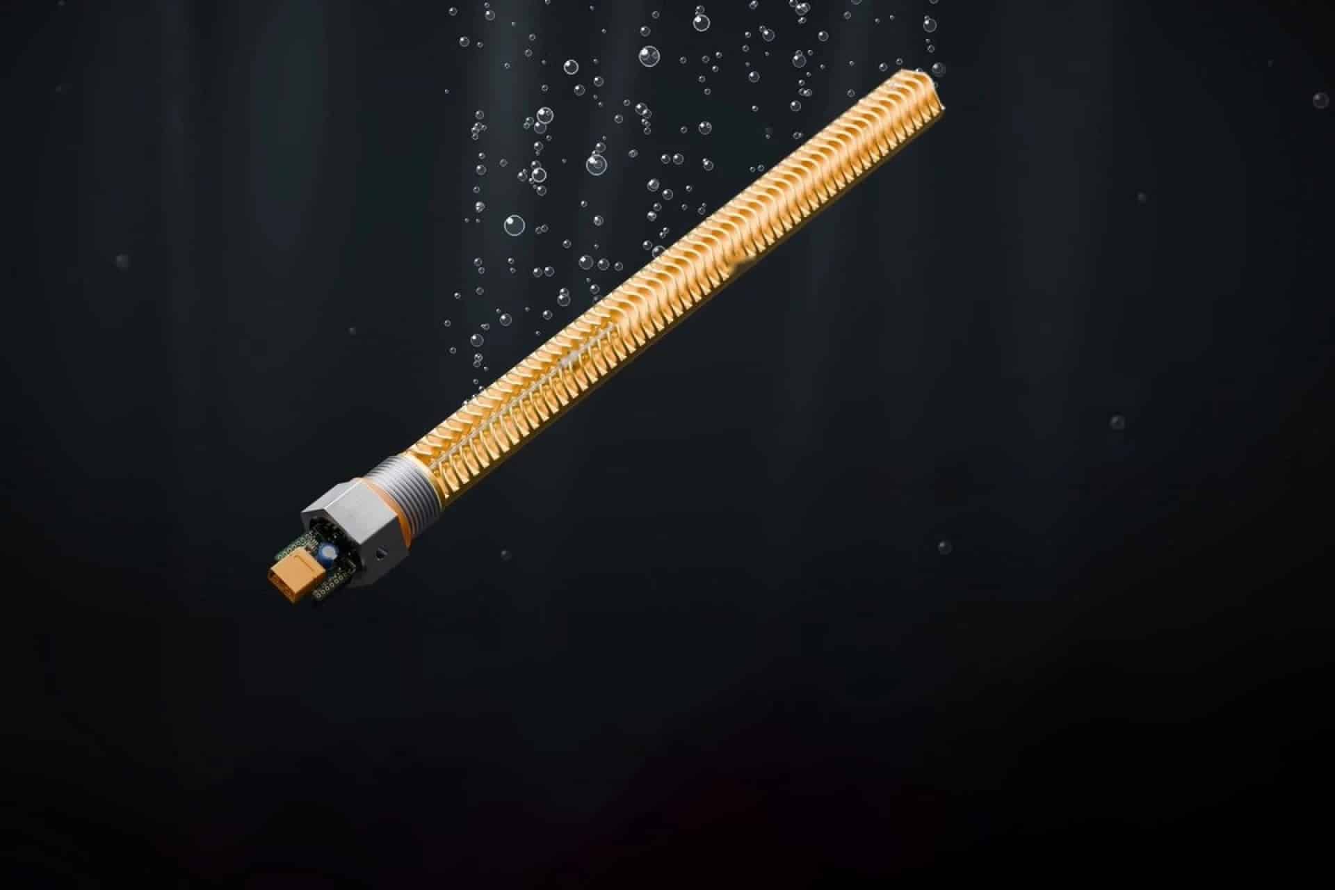 L'elemento dorato con i dissipatori e la scheda elettronica, su sfondo scuro con bolle d'acqua. Scaldabagno Bitcoin
