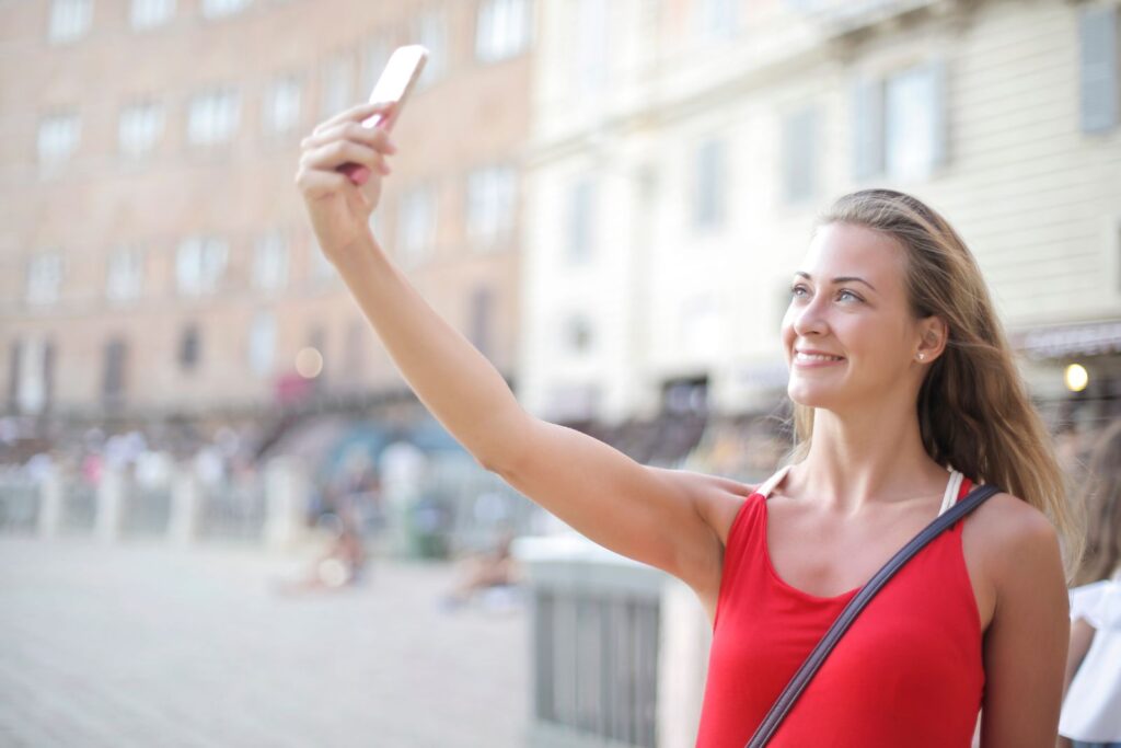 Un selfie di una donna con lo smartphone: la foto del volto da cui FaceAge stima l'età biologica