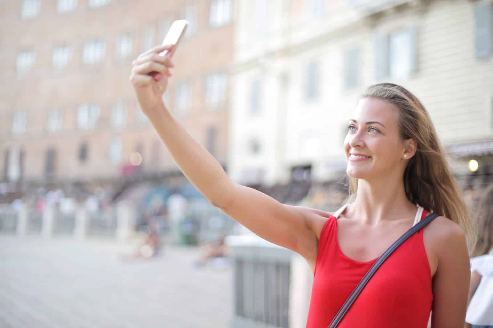 Un selfie di una donna con lo smartphone: la foto del volto da cui FaceAge stima l'età biologica