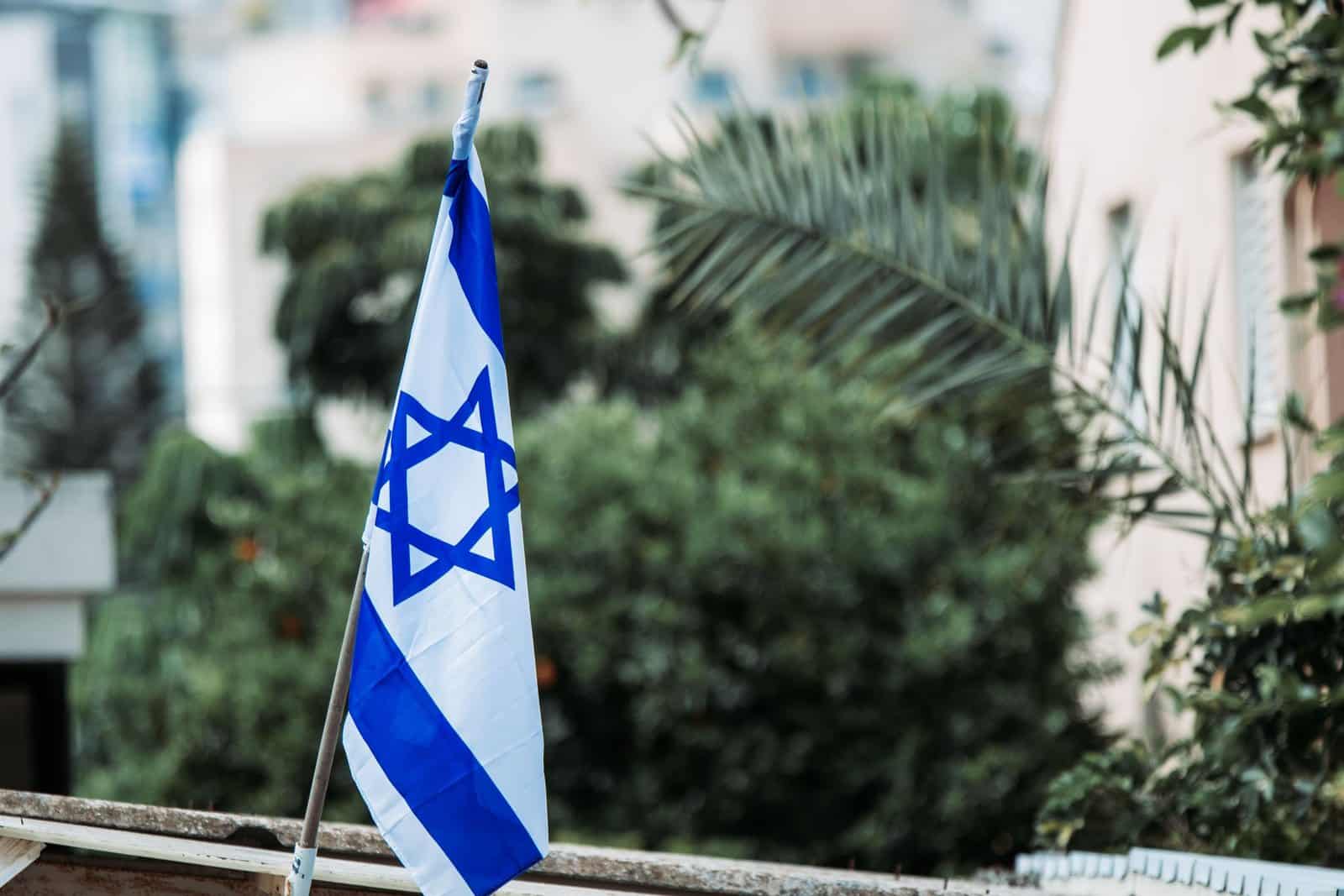 Soglia di sbarramento e Knesset: una bandiera israeliana tra gli alberi di una città