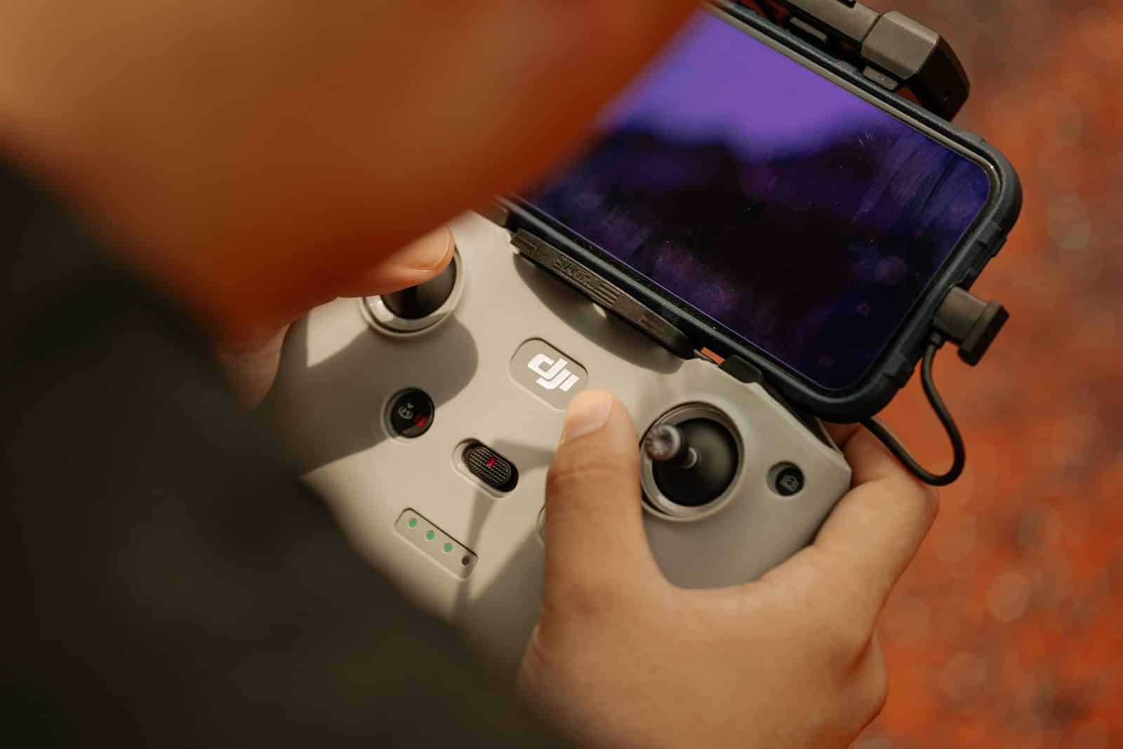 Mani su un radiocomando per droni con lo smartphone agganciato, immagine d'archivio sul collegamento Starlink dei droni