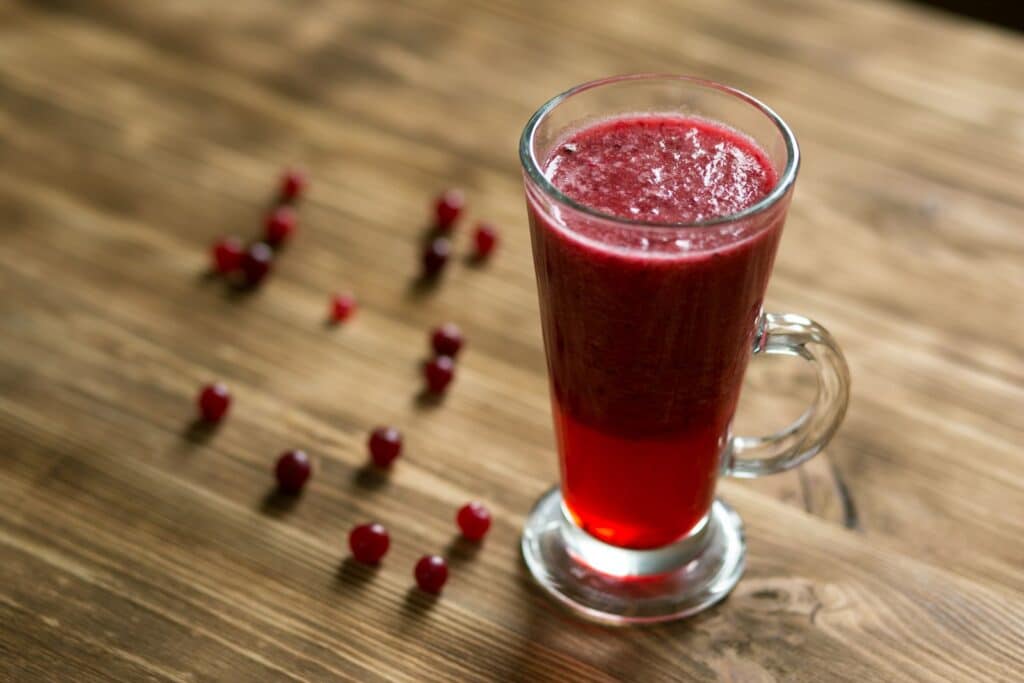 Un bicchiere alto di succo di mirtillo rosso su un tavolo di legno rustico