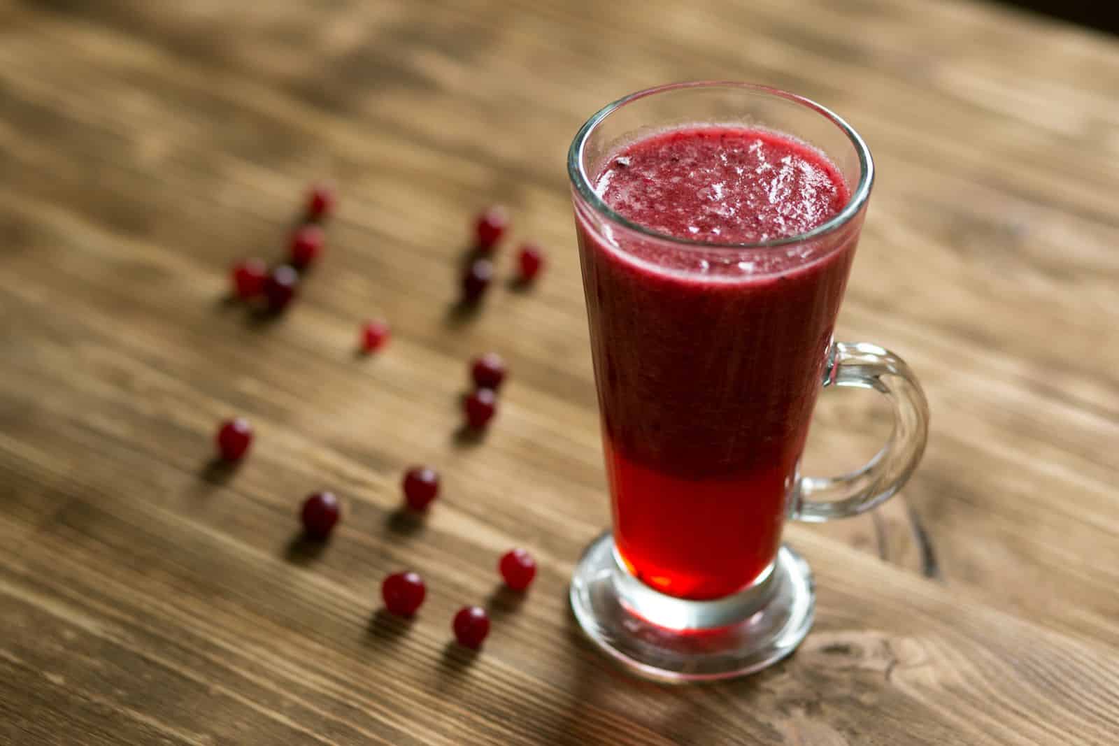 Un bicchiere alto di succo di mirtillo rosso su un tavolo di legno rustico