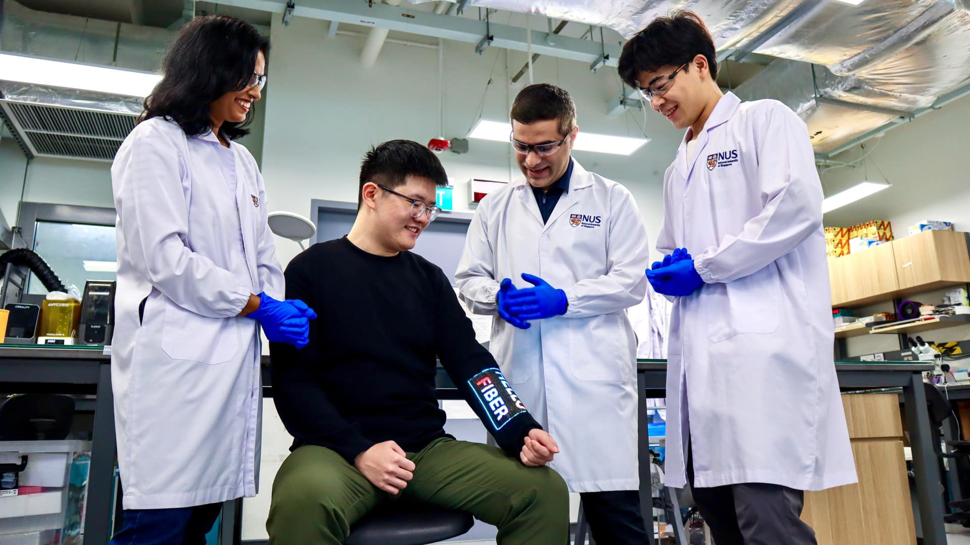 Ricercatori della NUS con la manica del touchscreen indossabile in laboratorio a Singapore